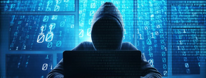 Hacker sits with his back to blue background of ones and zeroes.