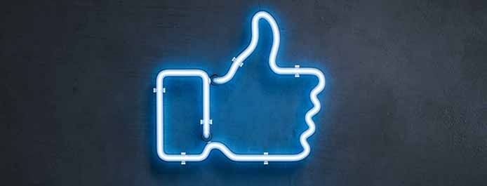 A blue neon sign shaped like Facebook's like button